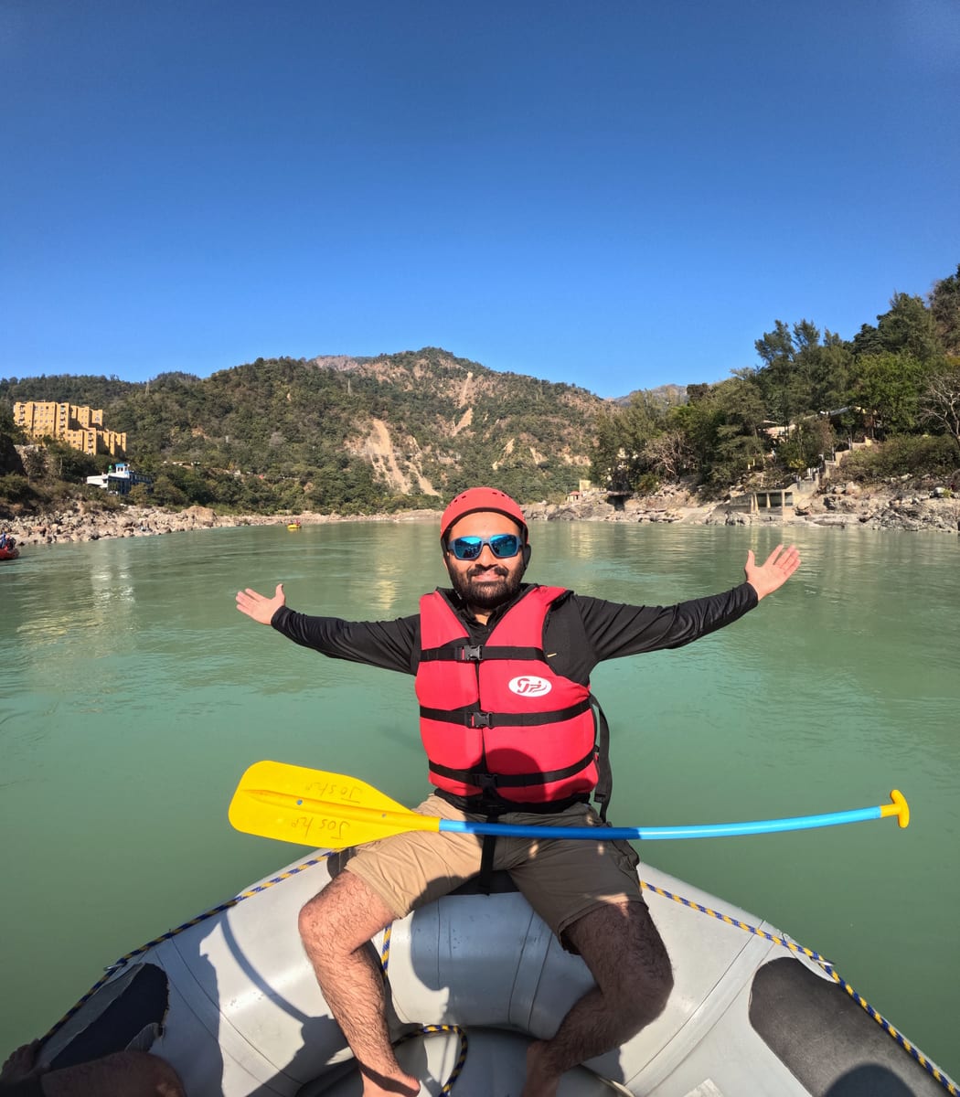 Priyank holding a paddle on a raft in Rishikesh